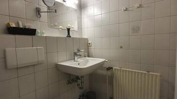 A bathroom with a toilet, sink, mirror, and tiled walls.