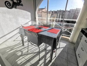 Ein Balkon mit Tisch, Stühlen und Blick auf Gebäude.