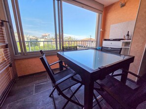 Ein Balkon mit Glastisch und Stühlen, Blick auf Gebäude und ein Fliesenboden.