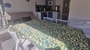 Una habitación con cama, una kitchenette pequeña, un comedor con sillas y una ventana.