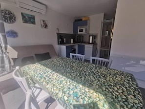 A room with a bed, a small kitchenette, a dining area with chairs, and a window. - Air-conditioned apartment, garden - 4 guests (Cap d'Agde)