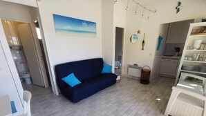 Un espacio habitable compacto con sofá, mesa de comedor y zona de cocina.