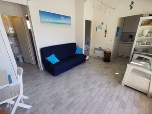 A compact living space with a sofa, a dining table, and a kitchen area. - Apartment with AC, pool, near beaches - 8 guests (Cap d'Agde)