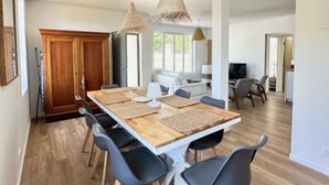 A modern dining area with a long wooden table, black chairs, and woven pendant lights. - House near the sea - 8 guests (Fouras)