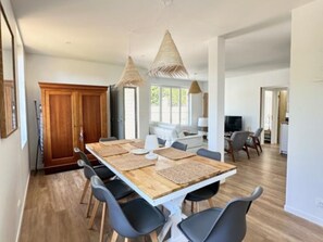 A modern dining area with a long wooden table, black chairs, and woven pendant lights. - House near the sea - 8 guests (Fouras)