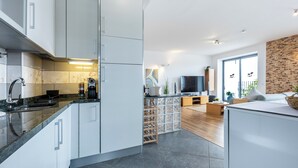 Eine moderne Küche mit weißen Schränken, einem eingebauten Backofen und einer Kaffeemaschine.
