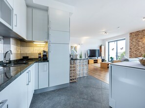 Eine moderne Küche mit weißen Schränken, einem eingebauten Backofen und einer Kaffeemaschine.