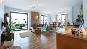 Ein geräumiger Wohnbereich mit Sofa, Couchtisch und Esstisch, großen Fenstern und einem Balkon.