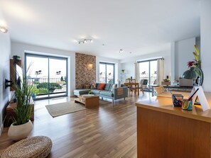 Ein geräumiger Wohnbereich mit Sofa, Couchtisch und Esstisch, großen Fenstern und einem Balkon.