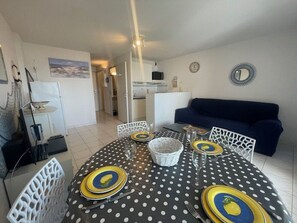 A dining area with a polka dot tablecloth, white chairs, and yellow plates. - Apartment with AC, parking - 4 guests (Cap d'Agde)