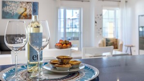 A dining table with a plate of mini quiches, a bottle of white wine, and a wine glass. - Lagos Line Apartment - sea views and Meia Praia (Lagos)