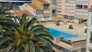 Un immeuble résidentiel doté d’une piscine, de balcons et d’un palmier.