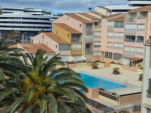 Ein Wohngebäude mit Swimmingpool, Balkonen und einer Palme.