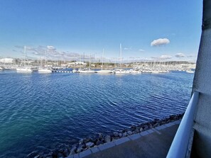 Ein Yachthafen mit vertäuten Booten, ruhigem Wasser und blauem Himmel.