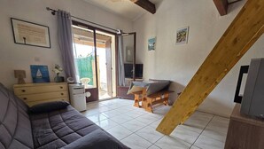 Ein Zimmer mit einer Couch, einem kleinen Tisch, einem Fernseher und einer hölzernen Bank.