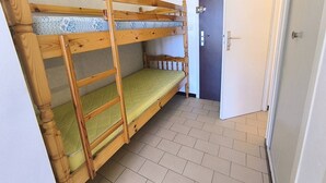 Ett rum med en våningssäng, en dörr och ett klinkergolv.