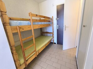 Ein Schlafzimmer mit Etagenbetten, einer Tür und einem gefliesten Boden.