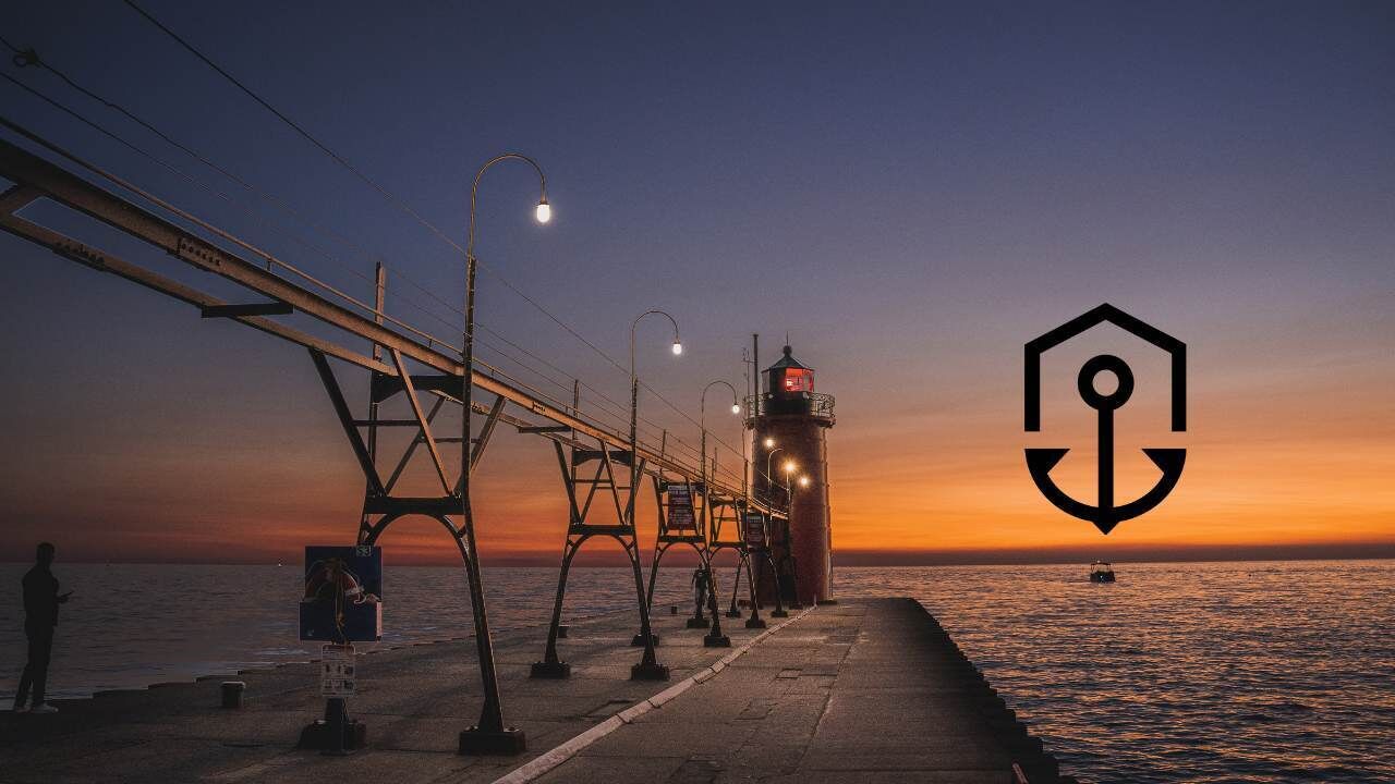 A pier with a lighthouse, street lamps, and a person standing by the water.