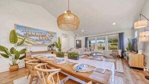 A spacious dining area with a long wooden table, chairs, and a hanging light fixture. - Harbor Haven | Hot Tub | Pool Access | Gym | Sauna (South Haven)