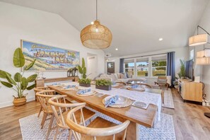 A spacious dining area with a long wooden table, chairs, and a hanging light fixture. - Harbor Haven | Hot Tub | Pool Access | Gym | Sauna (South Haven)