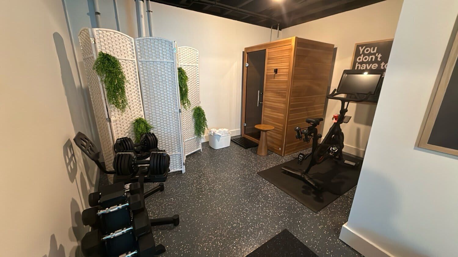 A gym with exercise equipment, a wooden door, and a motivational quote on the wall.
