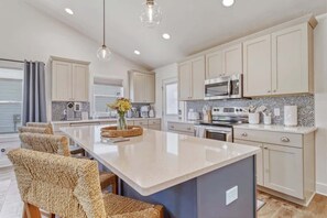 A modern kitchen with a central island, stainless steel appliances, and light-colored cabinetry. - Harbor Haven | Hot Tub | Pool Access | Gym | Sauna (South Haven)