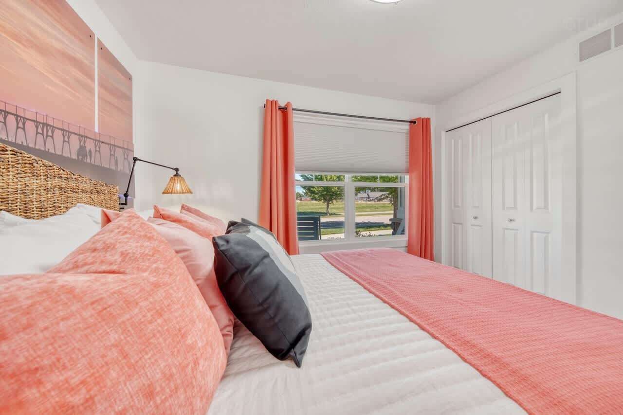 Une chambre à coucher avec un lit, une lampe, une fenêtre avec des rideaux et une vue sur l’extérieur.