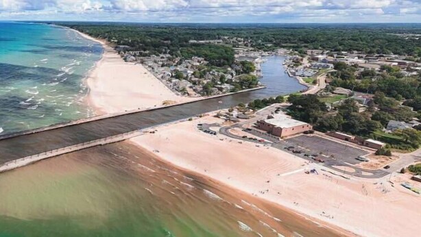 An aerial view of a coastal area with a beach, a bridge, and a town with buildings. - Harbor Haven | Hot Tub | Pool Access | Gym | Sauna (South Haven)