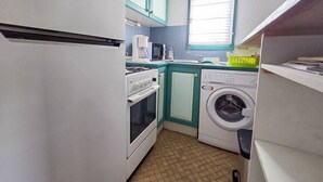Eine kleine Küche mit Kühlschrank, Herd, Mikrowelle und Waschmaschine.
