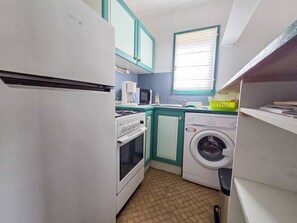Eine kleine Küche mit Kühlschrank, Herd, Mikrowelle und Waschmaschine.