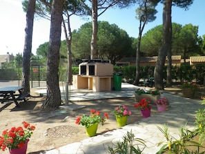 Eine Terrasse mit Grill, Picknicktisch und Topfpflanzen.