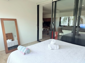 Ein Hotelzimmer mit Bett, Spiegel, Badezimmertür und Blick auf einen Essbereich.