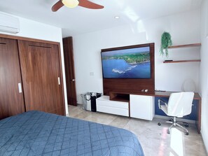 Un dormitorio con cama, televisor, escritorio y silla.