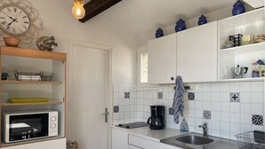 Une cuisine avec des armoires blanches, un four à micro-ondes, une machine à café et des carreaux décoratifs.