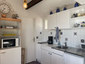 A kitchen with white cabinets, a microwave, a coffee maker, and decorative tiles. - 2-room apartment sea view - 4 guests (Cap d'Agde)