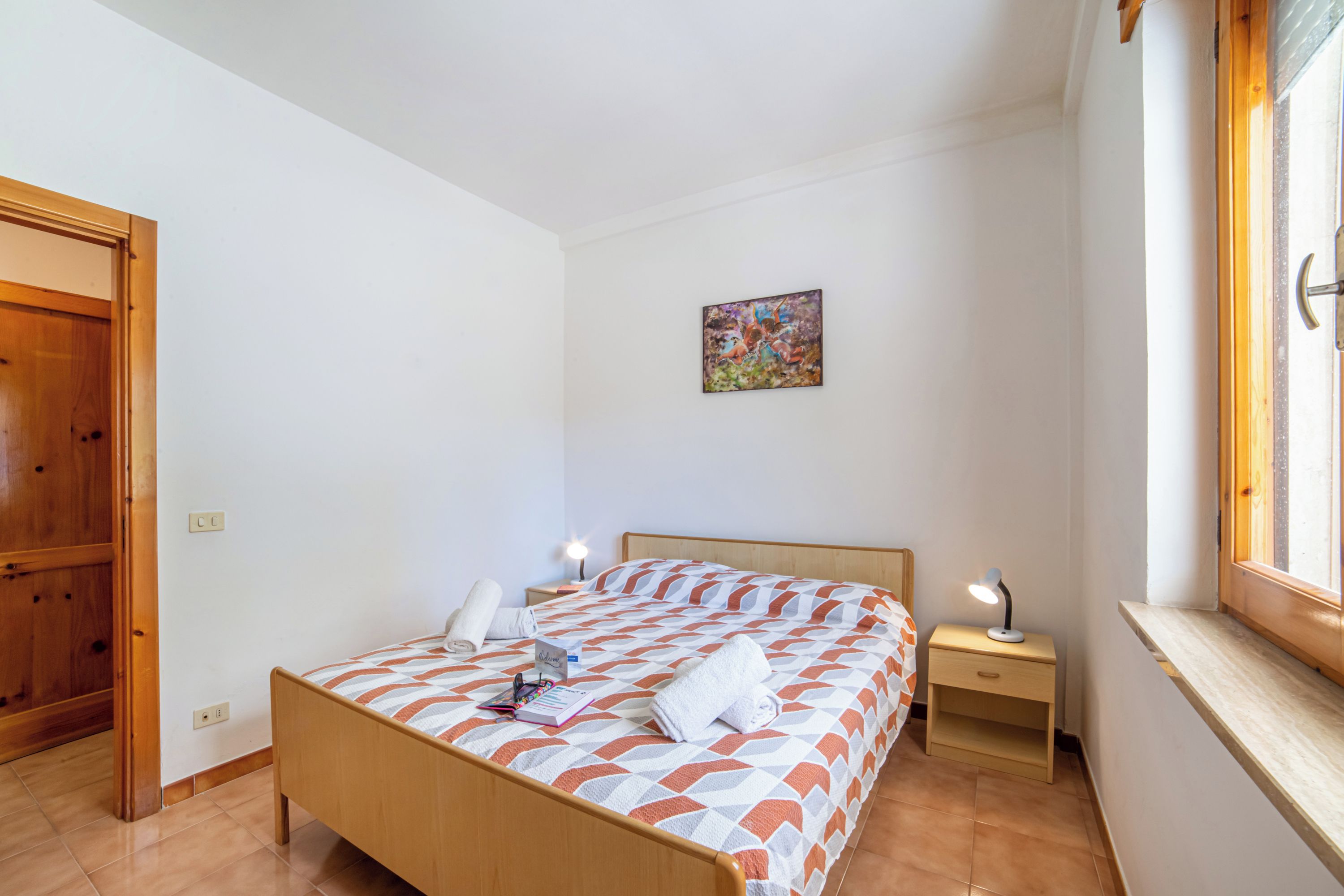 Une chambre à coucher avec un lit, une table de chevet, une fenêtre et une porte.