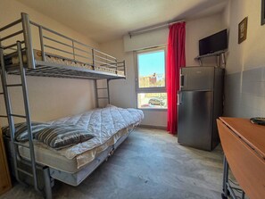 Ein Schlafraum mit Etagenbetten, einem Kühlschrank und einem Fernseher.