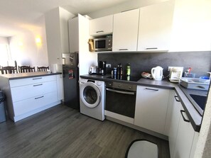 Eine kleine Küche mit Waschmaschine, Mikrowelle und Kaffeemaschine.