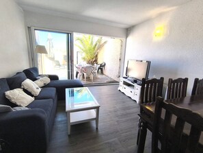 Ein Wohnzimmer mit einer Couch, einem Couchtisch, einer TV-Konsole und einem Essbereich mit Stühlen.