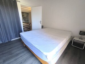 Ein Schlafzimmer mit einem Bett, einem Nachttisch, einer Lampe und einer Tür zu einem Badezimmer.