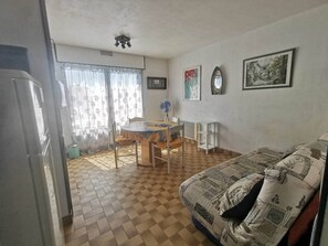 Ein kompakter Wohnraum mit Essbereich, einer Couch und einem Kühlschrank.
