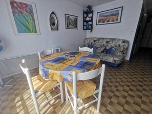 Ein Essbereich mit rundem Tisch, Stühlen, einer gemusterten Couch und Wandbildern.