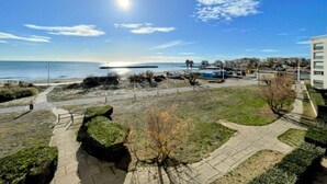A coastal area with a clear sky, a pathway leading to the beach, and a building with multiple floors. - Sea view apartment with parking - 4 guests (Cap d'Agde)