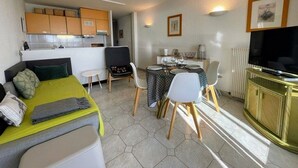 A compact room with a bed, a dining table with chairs, a kitchenette, and a television. - Sea view apartment with parking - 4 guests (Cap d'Agde)