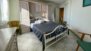 A bedroom with a bed, wardrobe, chair, and a small table. - Sea view apartment with parking - 4 guests (Cap d'Agde)