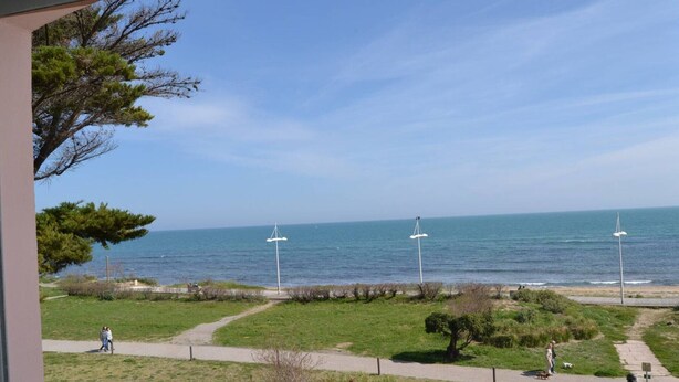 A coastal view from a balcony with a clear sky, a grassy area, and a path leading to the sea. - Sea view apartment with parking - 4 guests (Cap d'Agde)
