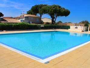 Ein rechteckiger Swimmingpool mit einer glatten, blauen Wasserfläche, umgeben von einer gefliesten Liegefläche.
