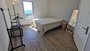 Een slaapkamer met een enkel bed, een radiator, een raam met uitzicht en een deur.