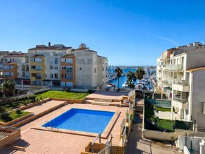 Ein Wohngebiet mit Schwimmbad, Mehrfamilienhäusern und einer Marina im Hintergrund.