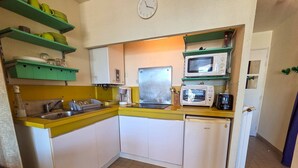 Eine kompakte Küche mit Spüle, Mikrowelle, Toaster und Kühlschrank.